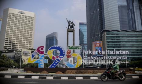 Pengendara motor melintas di dekat dekorasi Jakarta Hajatan 495 di kawasan Bundaran HI, Jakarta, Senin (20/6/2022). Dekorasi berupa tanaman bunga dan logo Jakarta Hajatan 495 di pinggir kolam Bundaran HI itu untuk menyambut HUT ke-495 Kota Jakarta pada 22 Juni 2022 mendatang.