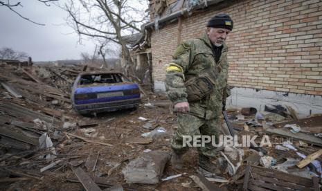 Andrey Goncharuk, 68, seorang anggota pertahanan teritorial, berjalan di halaman belakang sebuah rumah yang rusak akibat serangan udara Rusia, menurut penduduk setempat, di Gorenka, di luar ibu kota Kyiv, Ukraina, Rabu, 2 Maret 2022. 