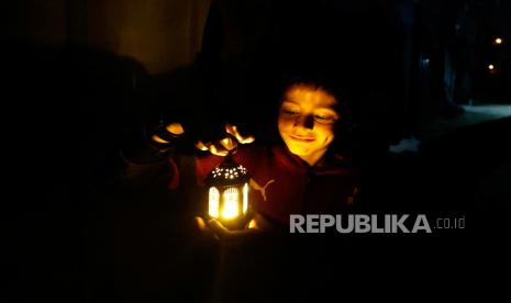 Seorang anak Palestina memegang lentera di tenda pengungsian mereka saat menyambut datangnya Ramadhan di Rafah, di selatan Jalur Gaza, Sabtu (9/3/2024).