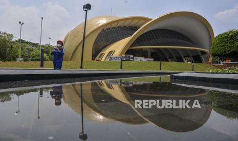 Pekerja berjalan dengan latar belakang Teater Keong Emas di Taman Mini Indonesia Indah (TMII), Jakarta, Rabu (28/9/2022). Proses revitalisasi TMII telah mencapai 98 persen dan direncanakan akan menjadi salah satu lokasi KTT G20. 