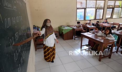 Guru memberi penjelasan kepada sejumlah siswa saat belajar Aksara Jawa di SD Negeri Kepatihan Solo, Jawa Tengah, Kamis (10/11/2022). Kegiatan belajar menulis dan membaca tersebut sebagai upaya melestarikan aksara jawa serta menjaga keberlangsungan kebudayaan Jawa. 