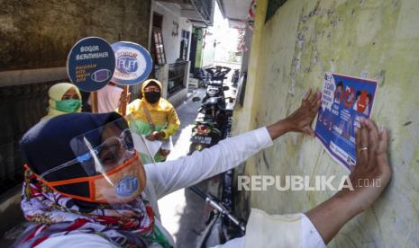 Petugas puskesmas menempelkan poster imbauan memakai masker saat sosialisasi gerakan 3M (memakai masker, mencuci tangan, dan menjaga jarak) di kawasan pemukiman warga Tanah Sareal , Kota Bogor, Jawa Barat, Kamis (1/10/2020). Sosialisasi gerakan 3M di kawasan perkampungan tersebut guna meningkatkan kesadaran masyarakat dalam pencegahan  penyebaran COVID-19. 