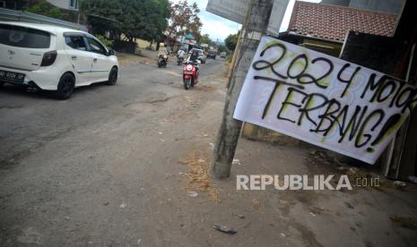 Spanduk protes terpasang sebagai bentuk protes jalan berlubang di Kelurahan Wirokerten, Bantul, Yogyakarta, Rabu (5/7/2023). Warga menanam pohon pisang di jalan berlubang serta memasang spanduk protes imbas kerusakan di Jalan Monumen Perjuangan. Selain itu, warga juga menandai lubang di jalan menggunakan cat putih. Panjang jalan yang rusak sekitar 300 meter. Warga berharap kerusakan jalan segera diperbaiki karena bisa membahayakan pengguna jalan.