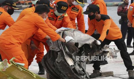 Anggota Badan Pencarian dan Penyelamatan Nasional (BASARNAS) memeriksa puing-puing pesawat Sriwijaya Air penerbangan SJ 182, yang ditemukan dari lokasi kecelakaan di perairan Jakarta, di pelabuhan Tanjung Priok di Jakarta, Indonesia, 19 Januari 2021. Penerbangan Sriwijaya Air SJ182 jatuh ke laut lepas pantai Jakarta pada tanggal 09 Januari 2021 sesaat setelah lepas landas dari Bandara Internasional Jakarta dalam perjalanan ke Pontianak di provinsi Kalimantan Barat.