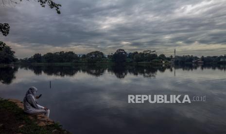 Seorang warga duduk di tepi Situ Cikaret dengan latar belakang awan mendung di Cibinong, Kabupaten Bogor, Jawa Barat, Kamis (11/11/2021). Badan Meteorologi, Klimatologi, dan Geofisika (BMKG) memberikan peringatan dini agar waspada akan cuaca ekstrim untuk curah hujan sedang hingga lebat yang diperkirakan terjadi di 28 wilayah di Indonesia diantaranya DKI Jakarta, Jawa Barat, Jawa Timur, dan Kalimantan Barat. 