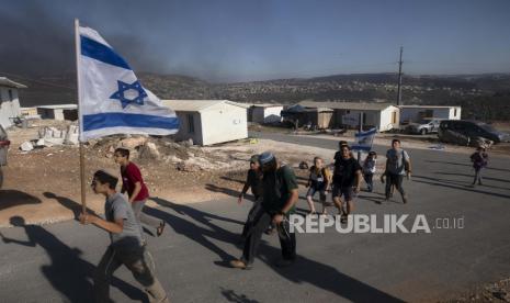 Pemukim Israel membawa bendera Israel di pos terdepan Eviatar dekat kota Nablus di Tepi Barat utara, Senin, 21 Juni 2021. Pemukim mendirikan pos terdepan bulan lalu dan mengatakan sekarang menjadi rumah bagi puluhan keluarga. Palestina mengatakan itu dibangun di atas tanah pribadi dan khawatir itu akan tumbuh dan bergabung dengan pemukiman besar lainnya di dekatnya.