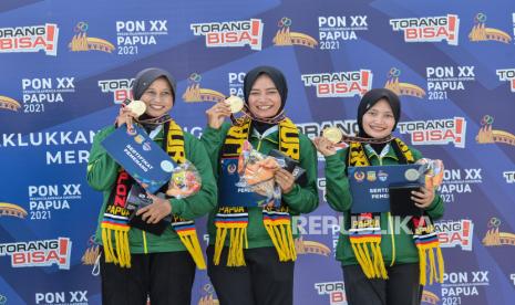 Atlet panahan putri Jawa Timur menunjukan  medali emas usai memanangkan pertandingan final panahan kelas recurve women team PON Papua di Lapangan Kampung Harapan, Sentani Kabupaten Jayapura, Papua, Selasa (5/10). Tim panahan Jawa TImur berhasil meraih medali emas pada panahan ketegori recurve women team disusul Papua medali perak, dan Jawa Barat medali perunggu. Republika/Thoudy Badai