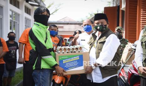 Wakil Gubernur Jawa Barat Uu Ruzhanul Ulum (kanan) secara simbolis menyerahkan bantuan sembako kepada ojol dan petugas Pos saat pelepasan bantuan sosial (Bansos) untuk warga Kota Banjar yang terdampak COVID-19 di Kantor Pos Kota Banjar, Rabu (29/4). Bansos senilai Rp500 ribu dari Pemda Provinsi Jabar merupakan salah satu dari sembilan pintu bantuan kepada warga terdampak pandemi COVID-19