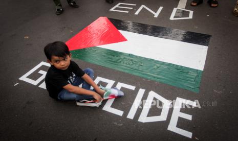 Seorang anak duduk di dekat pop art bergambarkan bendera Palestina saat aksi solidaritas untuk Palestina di depan Kedutaan Besar Amerika untuk Indonesia, Jakarta, Jumat (19/4/2024). Aksi yang digagas oleh para seniman yang mengatasnamakan Koalisi Musisi untuk Gaza dan KontraS tersebut untuk memberikan wadah bagi anak muda bersuara dan menuntut agar genosida di Palestina segera dihentikan.