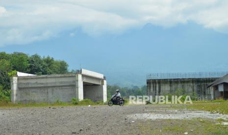 Pengendara motor melintas di dekat bangunan jembatan tol Padang - Pekanbaru yang ditinggalkan di Kapalo Hilalang, Kabupaten Padangpariaman, Sumatera Barat, Senin (23/08/2021). Berdasarkan surat Badan Pengatur Jalan Tol (BPJT) Kementerian PUPR Nomor BM.08-P/598,  pembangunan jalan tol Padang - Pekanbaru hanya sampai Sicincin, sementara sisa ruas jalan tol sepanjang 144 kilometer yang membentang dari Kapalo Hilalang, Padangpariaman ke Pangkalan, Kabupaten Limapuluhkota, pembangunannya ditangguhkan sementara. 