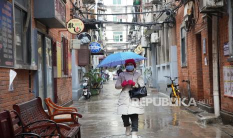 Seorang warga yang mengenakan masker untuk membantu melindungi diri dari COVID-19 berjalan di sepanjang jalan sempit di Wuhan di Provinsi Hubei, China tengah, Ahad, 23 Januari 2022. 