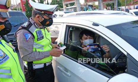 Polisi membagikan brosur terkait larangan mudik kepada pengendara.