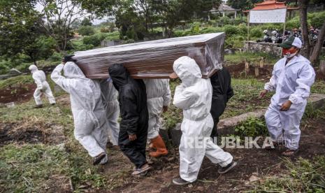 Sejumlah petugas pemakaman mengangkat peti jenazah pasien positif Covid-19.