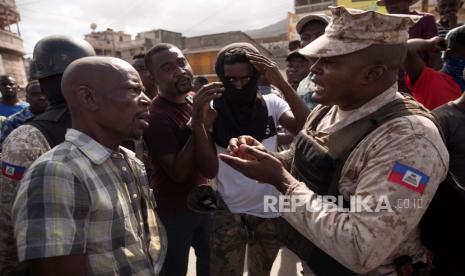  Seorang polisi berbicara kepada seorang pemrotes selama hari protes ketika upeti dibayarkan kepada Presiden Jovenel Moise yang terbunuh, di Cap-Haitien, Haiti, 22 Juli 2021. Para pengunjuk rasa yang menuntut keadilan bagi Moise mendirikan api unggun dan barikade di berbagai titik kota, di utara negara itu, tempat presiden dilahirkan. Sejauh ini, 26 orang telah ditangkap karena diduga terlibat dalam pembunuhan tersebut.