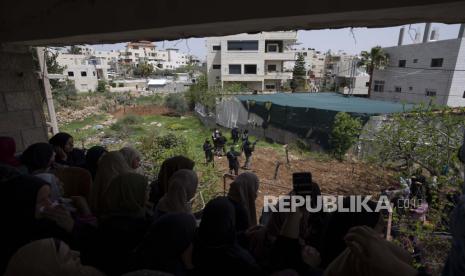  Malaysia Serukan OKI dan PBB Hentikan Kekejaman Israel terhadap Palestina. Foto: Para pelayat wanita melihat keluar dari balkon ke arah pria bersenjata Palestina yang menembak ke udara selama pemakaman Muhammad Ali Ahmed Ghoneim, 21 tahun, yang dibunuh hari Minggu oleh tentara Israel, di rumah keluarganya, di desa Tepi Barat. 