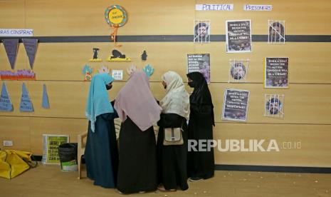 Gadis Muslim India memperbaiki poster sebelum diskusi panel bertema Hijab (jilbab) bertema Memetakan Ajaran Misoginis dan Perlawanan Wanita, yang diselenggarakan oleh Front Kampus India, di Bangalore, India, 12 April 2022. 