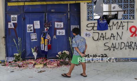 Seorang anak laki-laki berdiri di depan pintu masuk tribun untuk memberikan belasungkawa kepada para korban kerusuhan dan penyerbuan di Stadion Kanjuruhan di Malang, Jawa Timur, Indonesia, 04 Oktober 2022. Menurut Menteri Koordinator Politik, Hukum, dan Keamanan Indonesia Mahfud MD , pemerintah membentuk tim investigasi independen setelah 125 orang tewas dalam kerusuhan dan penyerbuan menyusul pertandingan sepak bola antara Arema FC dan Persebaya Surabaya di Jawa Timur pada 01 Oktober 2022.