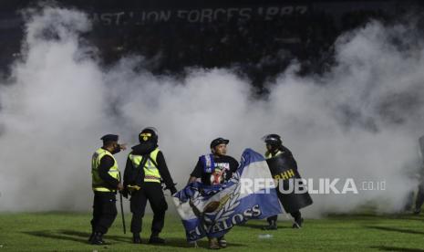  Seorang penggemar sepak bola memasuki lapangan saat petugas polisi berjaga-jaga selama kerusuhan setelah pertandingan sepak bola di Stadion Kanjuruhan di Malang, Jawa Timur, 01 Oktober 2022 (dikeluarkan pada 02 Oktober 2022). Sedikitnya 127 orang termasuk polisi tewas setelah suporter sepak bola Indonesia memasuki lapangan yang menyebabkan kepanikan dan injak-injak.