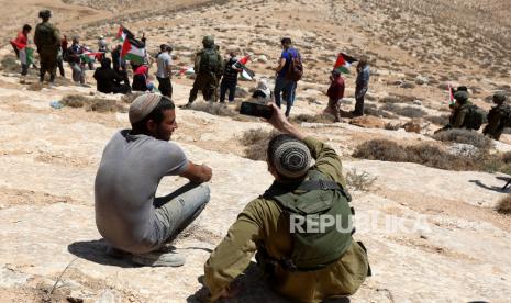  Seorang tentara Israel mengambil selfie dirinya dengan seorang pemukim selama protes warga Palestina di desa Tepi Barat Yatta, dekat Hebron, 21 Agustus 2020. Warga Palestina memprotes perjanjian perdamaian untuk membangun hubungan diplomatik antara Israel dan Uni Emirat Arab. Survei: Separuh Orang Yahudi Israel Ingin Punya Lebih Banyak Hak Dibanding Warga Palestina