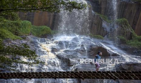 Seorang anak bermain di kawasan Wisata Curug Batu Templek, Cisanggarung Lebak, Kabupaten Bandung, Jawa Barat, Ahad (14/5/2023). Kawasan wisata yang memiliki lanskap alam air terjun yang terbentuk akibat pelapukan batu selama jutaan tahun tersebut ramai dikunjungi wisatawan pada akhir pekan.