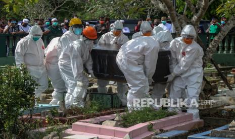 Petugas pemakaman membawa peti jenazah terkonfirmasi Covid-19. 