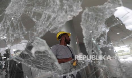 Seorang pria berdiri di dekat pecahan kaca di Istana Planalto setelah pendukung Bolsonaro mengambil alih Plaza de los Tres Poderes (Lapangan Tiga Kekuatan) untuk menyerbu gedung-gedung pemerintah, di Brasilia, Brasil, 09 Januari 2023. Ratusan pendukung mantan Presiden Brasil Jair Bolsonaro pada 08 Januari menyerbu markas besar Kongres Nasional, dan juga Mahkamah Agung dan Istana Planalto, pusat Kepresidenan Republik, dalam demonstrasi yang menyerukan intervensi militer untuk menggulingkan Presiden Luiz Inacio Lula da Silva. Massa menerobos barisan pasukan keamanan dan memaksa masuk ke atap gedung Kamar Deputi dan Senat, dan beberapa masuk ke dalam markas legislatif. Sejauh ini, pihak berwenang menahan beberapa orang yang terlibat dalam aksi kekerasan yang dikutuk secara luas oleh semua lembaga Brasil dan komunitas internasional.