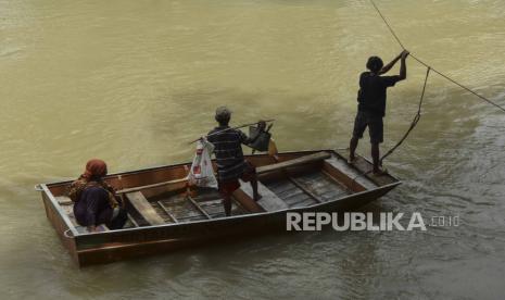 Dua warga menggunakan perahu menyeberang saat menyeberangi Sungai Ciseel di Desa Ciparay, Kecamatan Cidolog, Kabupaten Ciamis, Jawa Barat, Senin (14/11/2022). Warga terpaksa menggunakan perahu tarik untuk menyeberangi sungai akibat jembatan gatung rusak diterjang banjir bandang. 