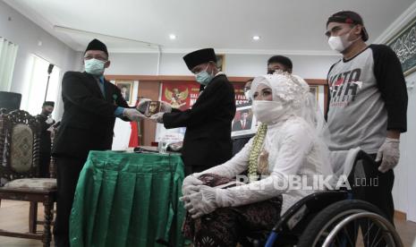 Penghulu menyerahkan buku nikah kepada pengantin saat acara Nikah Gratis di KUA Sewon, Bantul, DI Yogyakarta, Selasa (8/6/2021). Nikah Gratis yang digelar oleh Forum Ta