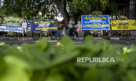 Sejumlah warga beraktivitas di dekat deretan karangan bunga ucapan belasungkawa atas wafatnya Wali Kota Bandung Oded M Danial di Jalan Dalem Kaum, Kota Bandung, Ahad (12/12). Ratusan karangan bunga tersebut sebagai bentuk penghargaan, penghormatan sekaligus duka cita atas wafatnya Wali Kota Bandung Oded M Danial pada Jumat (10/12). Foto: Republika/Abdan Syakura