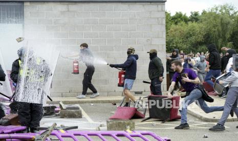 Massa aksi menembakan alat pemadam kebakaran ke arah petugas polisi saat protes anti-imigrasi di luar Holiday Inn Express di Rotherham, Inggris, Ahad (4/8/2024).