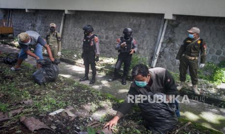 Tim gabungan Satpol PP, Polisi dan TNI menghukum warga yang kedapatan tidak memakai masker dengan membersihkan sampah saat Operasi Razia Masker di Jalan Brigjen Sudiarto, Solo, Jawa Tengah, Rabu (13/1/2021). Razia masker rutin selama Pemberlakukan Pembatasan Kegiatan Masyarakat (PPKM) tersebut dilakukan untuk meningkatkan kesadaran masyarakat pentingnya menerapkan protokol kesehatan sebagai upaya pencegahan penyebaran COVID-19. 