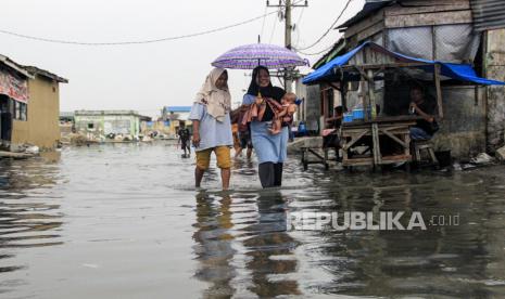 Sejumlah warga melintasi genangan air saat banjir  rob di Medan Belawan, Sumatera Utara, Rabu (27/3/2024). Badan Meteorologi Klimatologi dan Geofisika (BMKG) Stasiun Meteorologi Klas II Maritim Belawan memperkirakan banjir rob yang melanda daerah tersebut akan berlangsung hingga 30 Maret 2024 dan meminta masyarakat agar waspada dengan tinggi air yang mencapai 2,6 meter. 