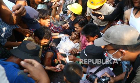  Pengunjuk rasa anti-kudeta mengepung seorang pria yang terluka di Hlaing Thar Yartownship di Yangon, Myanmar Minggu, 14 Maret 2021. 