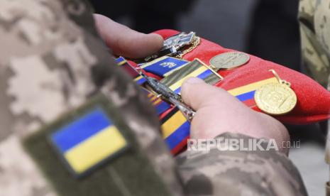 Seorang prajurit memegang dekorasi militer selama prosesi pemakaman prajurit Ukraina Oleksiy Lunyov di Yuzhne, wilayah Odessa, Ukraina, Ahad, 27 Maret 2022. 