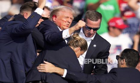 Kandidat presiden dari Partai Republik Donald Trump dibantu oleh  agen Dinas Rahasia AS menuruni turun panggung usai ditembak saat kampanye di Butler, Pennsylvania, AS, Sabtu (13/7/2024).