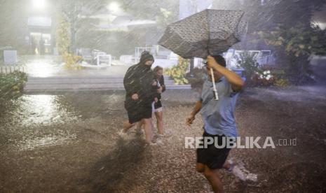  Orang-orang melewati hujan lebat dan jalan yang banjir di Pusat Tenis Nasional Billie Jean King saat sisa-sisa Badai Ida menghantam daerah itu di Flushing Meadows, New York, AS, 1 September 2021.