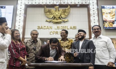 Menkumham Yasonna Laoly (tengah) didampingi Ketua Badan Legislasi (Baleg) DPR Supratman Andi Agtas (ketiga kanan), anggota DPD Dedi Iskandar Batubara (kedua kanan) dan sejumlah anggota Baleg DPR menandatangani dokumen usai mengikuti rapat pleno dan rapat kerja bersama Badan Legislas DPR dan DPD di Kompleks Parlemen Senayan, Jakarta, Senin (12/12/2022). Rapat tersebut membahas Prolegnas RUU Prioritas Tahun 2023. 