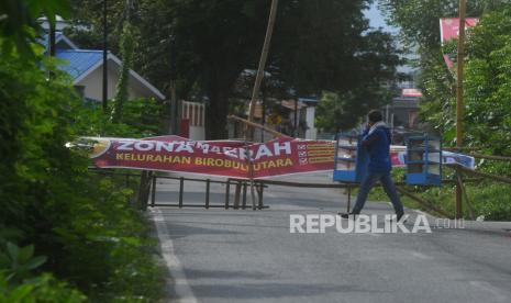 Seorang pedagang roti melintas dekat penutupan sebuah jalan menuju kawasan permukiman yang masuk ke dalam zona merah Covid 19 (ilustrasi)