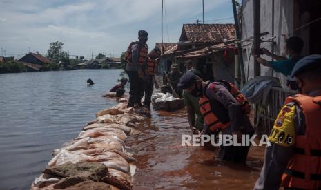 Sejumlah petugas gabungan dari Kepolisian Brimob Batalyon B Pelopor Pekalongan, TNI Kodim 0710 Pekalongan, BPBD Kota Pekalongan dan relawan warga bergotong royong membawa tumpukan karung di Tirto Gang 12, Pekalongan, Jawa Tengah, Selasa (24/5/2022). Petugas gabungan bergotong royong membuat tanggul darurat dari tumpukan karung akibat sejumlah ruas tanggul Sungai Meduri jebol sepanjang sekitar 13 meter di sekitar Tirto Gang 12 yang berimbas meluapnya air dan tingginya air laut pasang yang menyebabkan banjir rob yang merendam puluhan rumah dengan ketinggian antara 40-70 centimeter. 