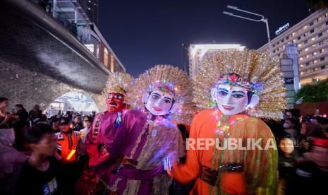 Warga menyaksikan pertunjukan karnaval saat gelaran Car Free Night di kawasan Bundaran Hotel Indonesia, Jakarta, Ahad (31/12/2023). Dalam rangka menyambut perayaan Tahun Baru 2024, Pemerintah Provinsi (Pemprov) DKI Jakarta menghadirkan sejumlah atraksi di antaranya 3D video mapping, konfigurasi drone, water mist, Jakarnaval, serta belasan panggung hiburan di sepanjang Jalan Sudirman-Thamrin.