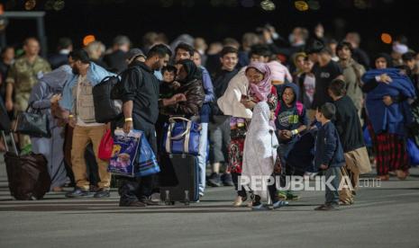 Keluarga yang dievakuasi dari Kabul, Afghanistan, berjalan menjauh dari pesawat angkatan udara AS setelah tiba di Bandara Internasional Pristina ibukota Kosovo pada hari Minggu, 29 Agustus 2021.