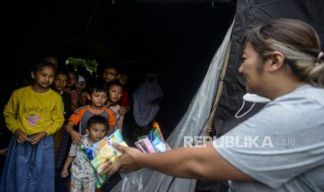 Relawan memberikan cemilan untuk anak-anak di kawasan Cijendil, Kecamatan Cugenang, Cianjur, Jawa Barat, Rabu (23/11/2022). Anak-anak menjadi salah satu korban terbanyak pada bencana gempa bumi berkekuatan 5,6 SR. Tercatat dari 271 korban jiwa pada bencana tersebut 37 persennya merupakan anak-anak. Republika/Putra M. Akbar