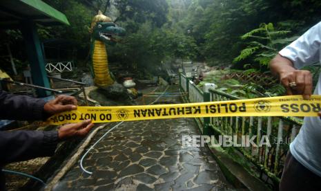 Petugas memasang garis polisi di tempat pemandian air panas pancuran 13 Obyek Wisata Guci, Kabupaten Tegal, Jawa Tengah, Sabtu (25/2/2023). Tempat pemandian air panas pancuran 13 penuh ditutup sementara akibat penuh pasir dan sejumlah pipa rusak sehingga suplai air bersih di tempat penginapan terhambat pasca banjir bandang Jumat (24/2/2023) malam. ANTARA FOTO/Oky Lukmansyah/hp.