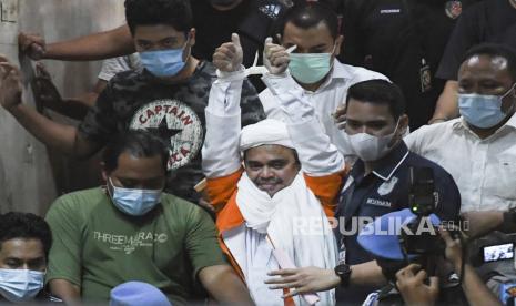 Pendiri Front Pembela Islam (FPI) Habib Rizieq Shihab berjalan menuju mobil tahanan usai diperiksa di Mapolda Metro Jaya, Jakarta, Ahad (13/12/2020) dini hari WIB.