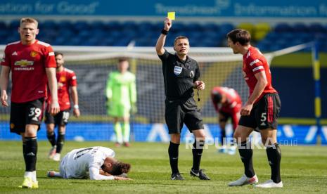 Harry Maguire (Kanan) dari Manchester United menerima kartu kuning setelah mendapat tantangan dari Tyler Roberts (2-L) dari Leeds selama pertandingan sepak bola Liga Utama Inggris antara Leeds United dan Manchester United di Leeds, Inggris, 25 April 2021.