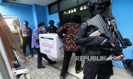 Personel Brimob berjaga saat proses bongkar muatan truk yang mengangkut vaksin COVID-19 Sinovac di kantor Dinas Kesehatan (Dinkes) Provinsi Jawa Timur, Surabaya, Jawa Timur, Senin (4/1/2021). Sebanyak 77.760 dosis vaksin COVID-19 Sinovac tiba di kantor tersebut dan selanjutnya disimpan di ruang pendingin atau cold room. 