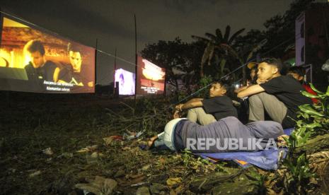 Sejumlah anak tanpa menggunakan masker menonton film layar tancap di kawasan Sawangan, Depok, Jawa Barat, Sabtu (11/7/2020). Layar tancap atau bioskop terbuka menjadi alternatif bagi warga untuk menonton film di tengah penerapan Pembatasan Sosial Berskala Besar (PSBB) Transisi kawasan Jabodetabek. 