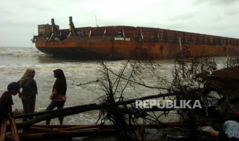 Sejumlah warga berdiri di samping kapal Tongkang yang terdampar, di Pantai Utara, Martoloyo, Tegal, Jawa Tengah, Senin (7/12). Kementerian ESDM menaikkan target produksi batu bara dari 550 juta ton menjadi 625 juta ton. 