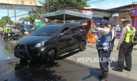 Polisi menghentikan pengendara mobil yang masuk Kota Surabaya untuk diperiksa identitasnya di Jalan Rungkut Menanggal, Surabaya, Jawa Timur, Ahad (26/4).