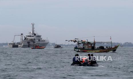 Sebuah kapal penangkap ikan (kanan) berlayar melewati operasi pencarian dan penyelamatan di dekat lokasi yang diduga kecelakaan penerbangan Sriwijaya Air SJ182 di perairan Jakarta, Indonesia, 10 Januari 2021. Kontak dengan penerbangan Sriwijaya Air SJ182 hilang pada 09 Januari 2021 tak lama setelah kejadian tersebut. pesawat lepas landas dari Bandara Internasional Jakarta dalam perjalanan ke Pontianak di provinsi Kalimantan Barat.